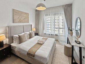 A modern hotel room with a large bed, a bedside table with a lamp, a desk with a mirror, and a window with sheer curtains. - Downtown Dubai Escape | 1BR at 29 Boulevard (Dubai)