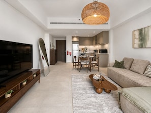 Ein modernes Wohnzimmer mit Flachbildfernseher, Couch, Couchtisch und einem Essbereich mit Stühlen und Tisch.