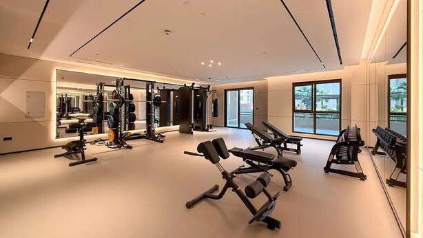 Ett modernt gym med olika typer av träningsutrustning, stora fönster och en stilren, minimalistisk inredning.