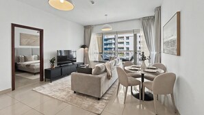Een moderne woonkamer met een bank, televisie en een eetgedeelte met stoelen en een tafel.