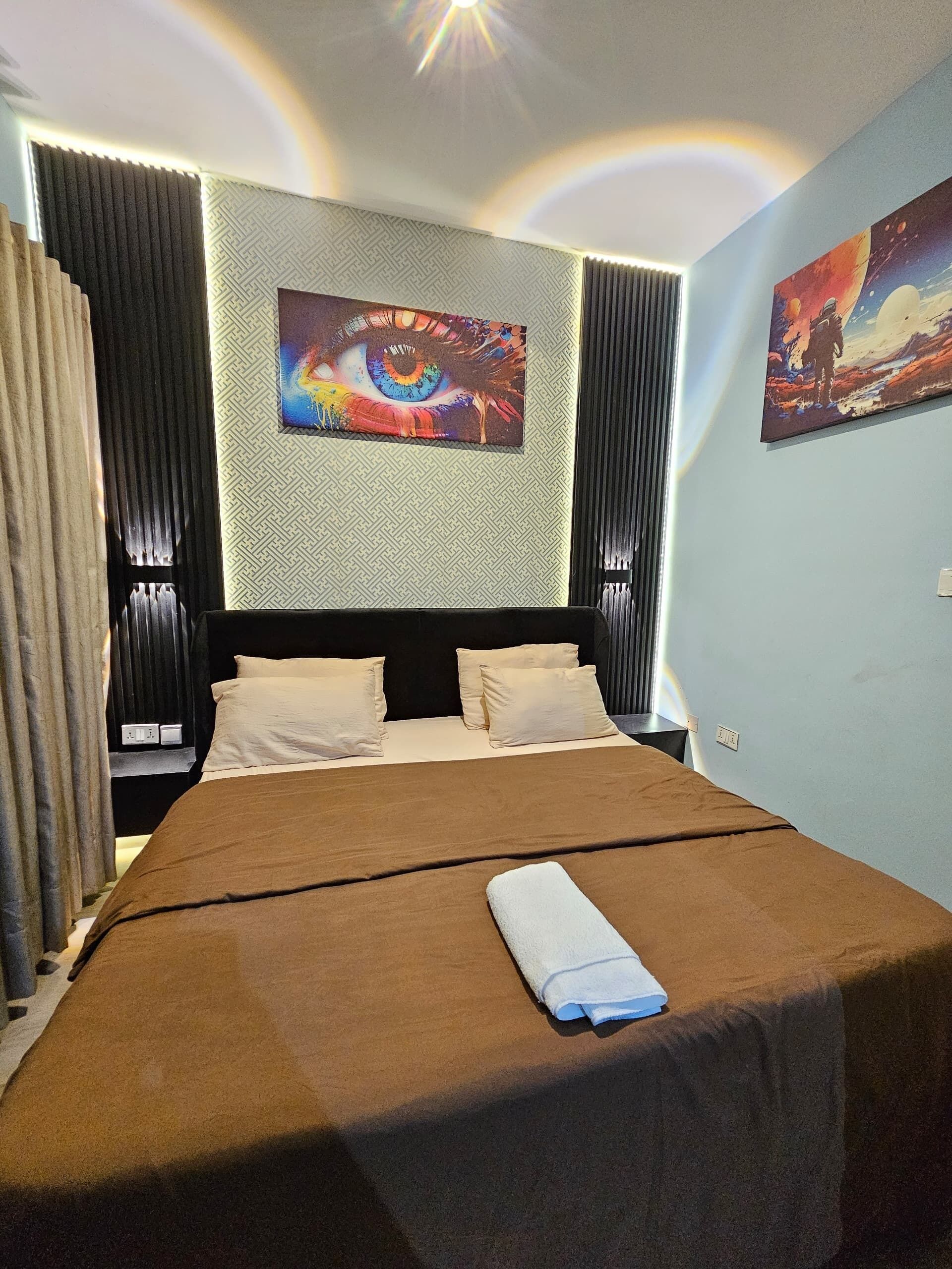 Ein Hotelzimmer mit einem großen Bett, einem geometrisch gemusterten Kopfteil und zwei an der Wand hängenden Bildern.