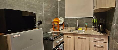 A compact kitchen with a refrigerator, stove, and microwave.