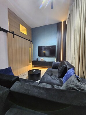 Una sala de estar moderna con una televisión de pantalla plana montada en la pared, un sofá y una mesa de centro.