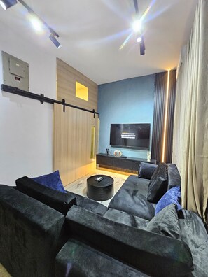 A modern living room with a sectional sofa, a flat-screen TV, and a coffee table. - Eastlands - 1 bedroom apartment, Lekki Phase 1. (Lekki)