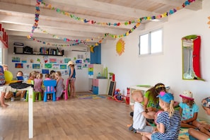 A classroom with children engaged in activities, wooden floors, and colorful decorations.