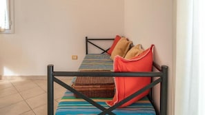 A single bed with a black metal frame, a striped bedspread, and two pillows.