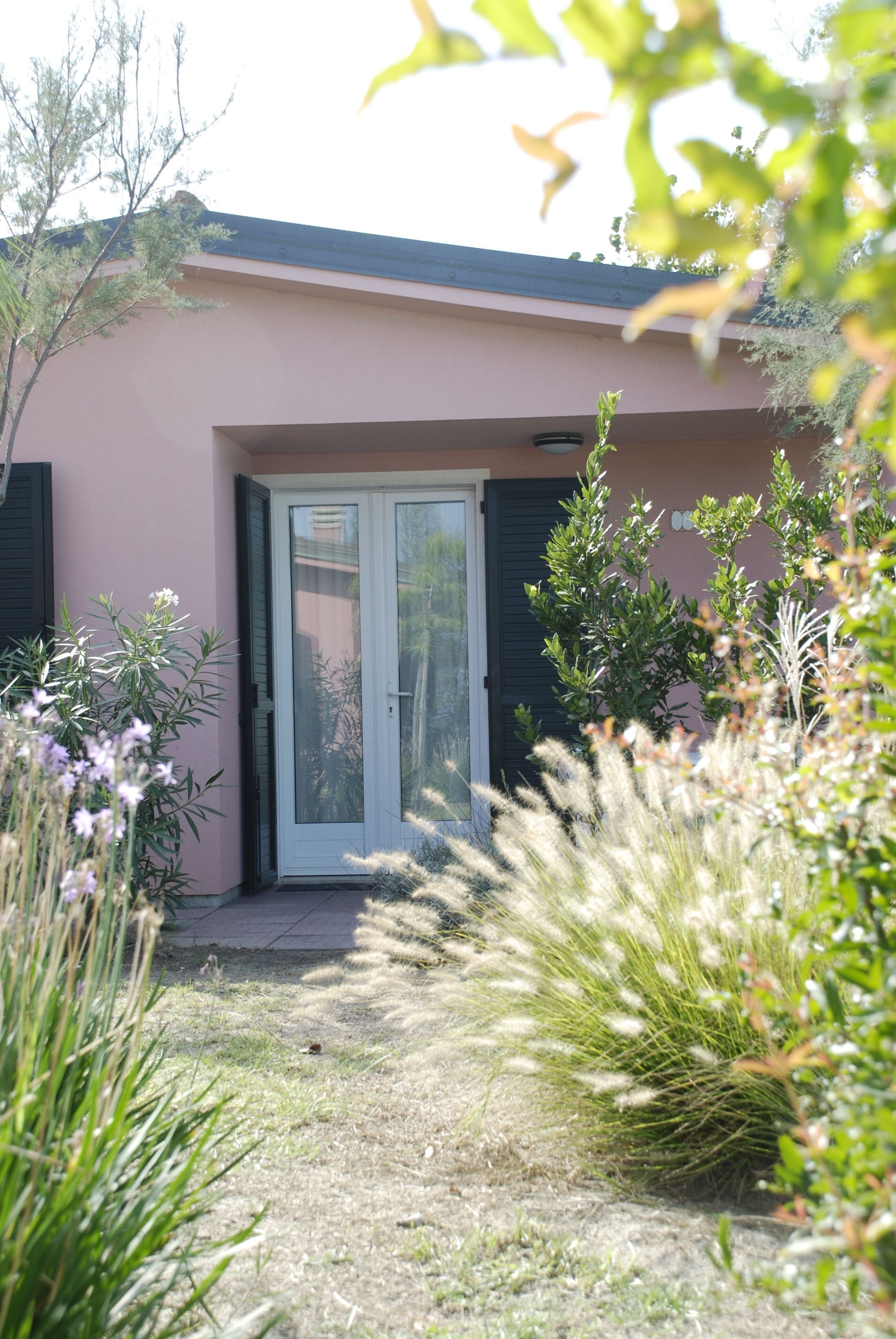 A house with a front door, a small garden, and a clear sky.