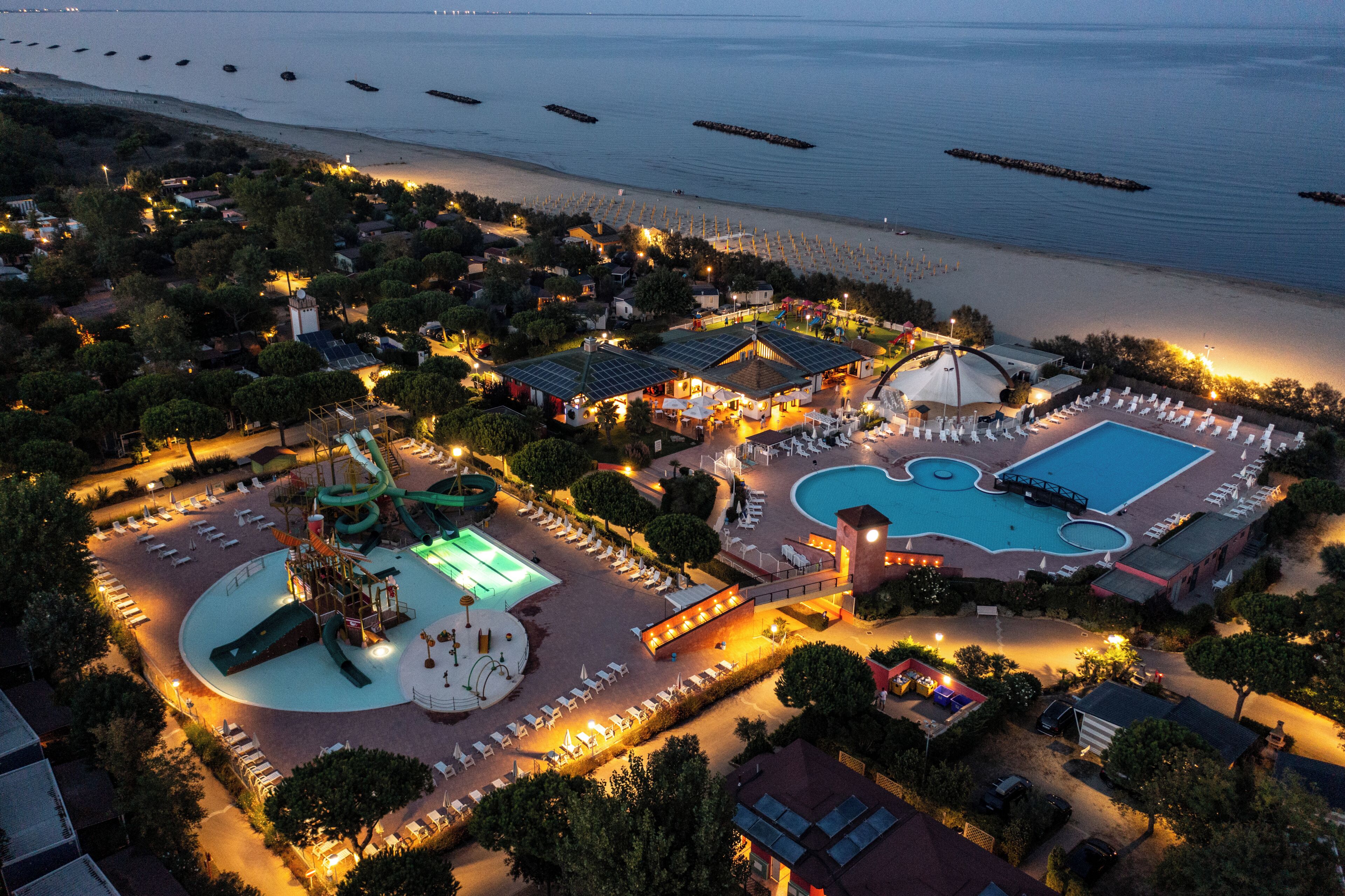 An aerial view of a resort with a swimming pool, water park, and beach area.