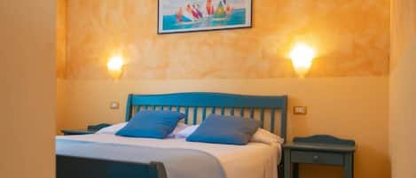 A bed with a headboard, two pillows, a bedside table, and a wall-mounted light fixture.