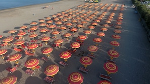 A beach with numerous sun umbrellas and lounge chairs arranged in rows.