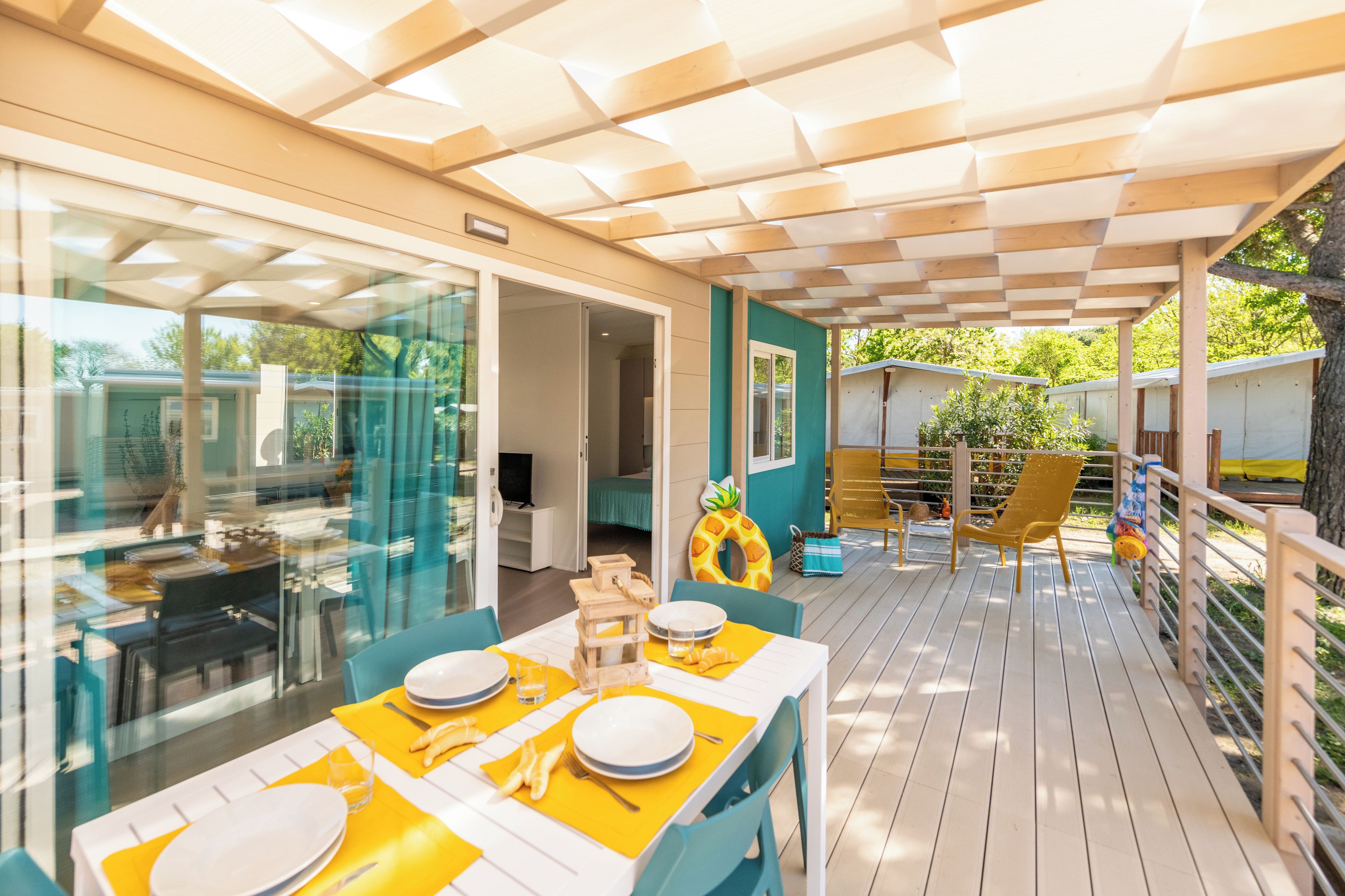 An outdoor dining area with tables and chairs, a glass partition, and a view of the surrounding landscape.