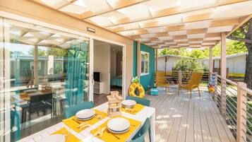 An outdoor dining area with tables and chairs, a glass partition, and a view of the surrounding landscape.
