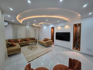 Una sala moderna con un conjunto de sofás, una mesita de centro y un televisor de pantalla plana montado en la pared.