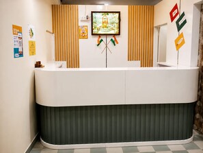 Un mostrador de recepción con un televisor de pantalla plana montado encima, flanqueado por listones verticales de madera.