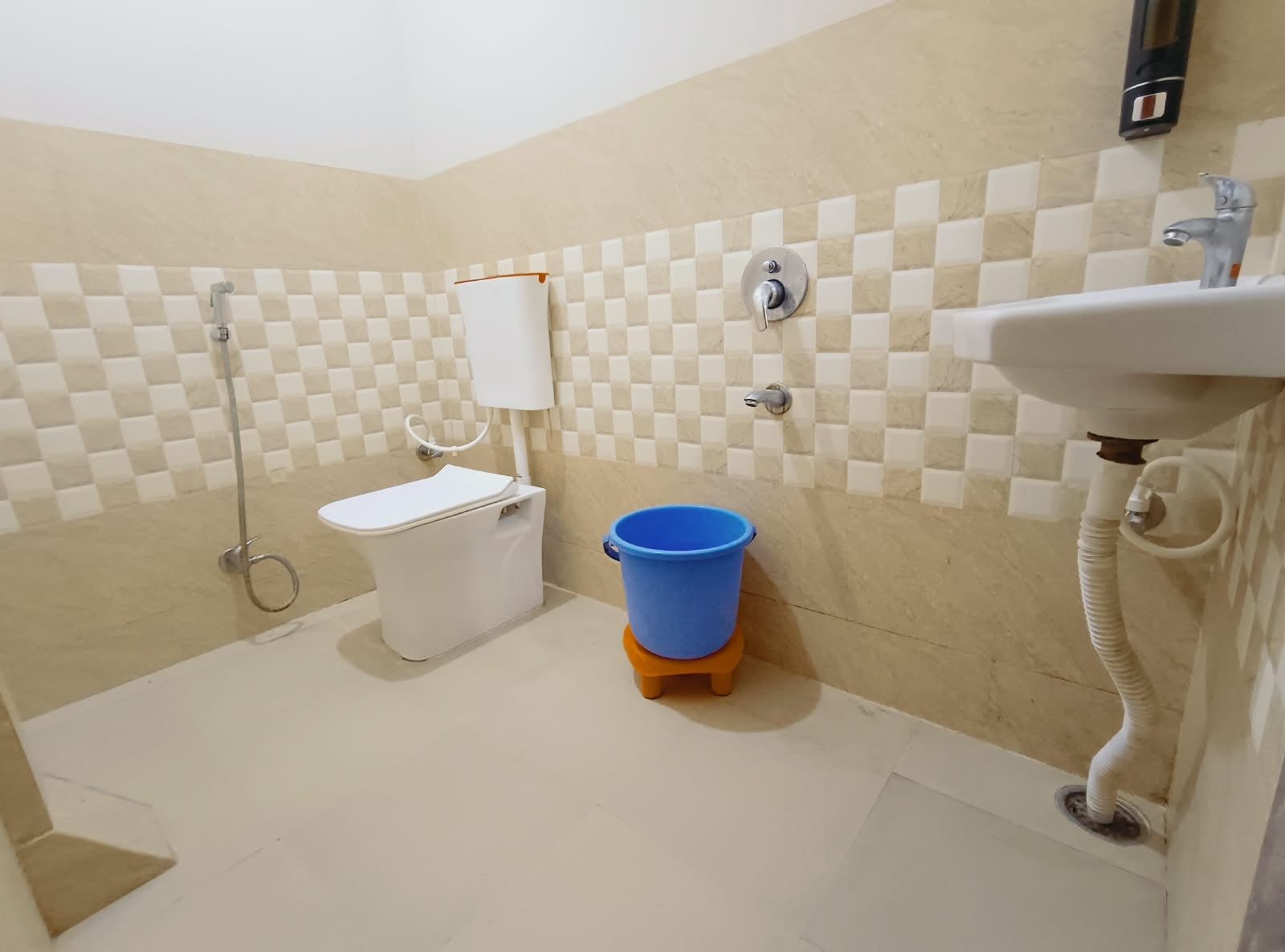 Ein Badezimmer mit Toilette, einem blauen Eimer, einem Waschbecken und einer Dusche.