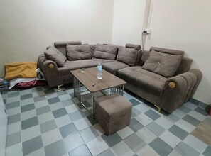 A living room with a brown sofa set, a small wooden coffee table, and a checkered floor.
