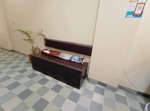 Un suelo a cuadros, un banco, una planta en maceta y una pared con un aviso.