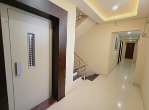 Un interior moderno con una escalera, una puerta con ventana y un pasillo que conduce a otra habitación.