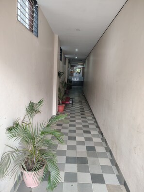 A hallway with checkered flooring, potted plants, and a door at the end.