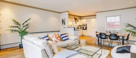A modern living room with a sofa, coffee table, and dining area.