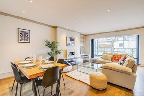 Un salon moderne avec un canapé, une table basse et un coin repas comprenant des chaises et une table mise pour le repas.