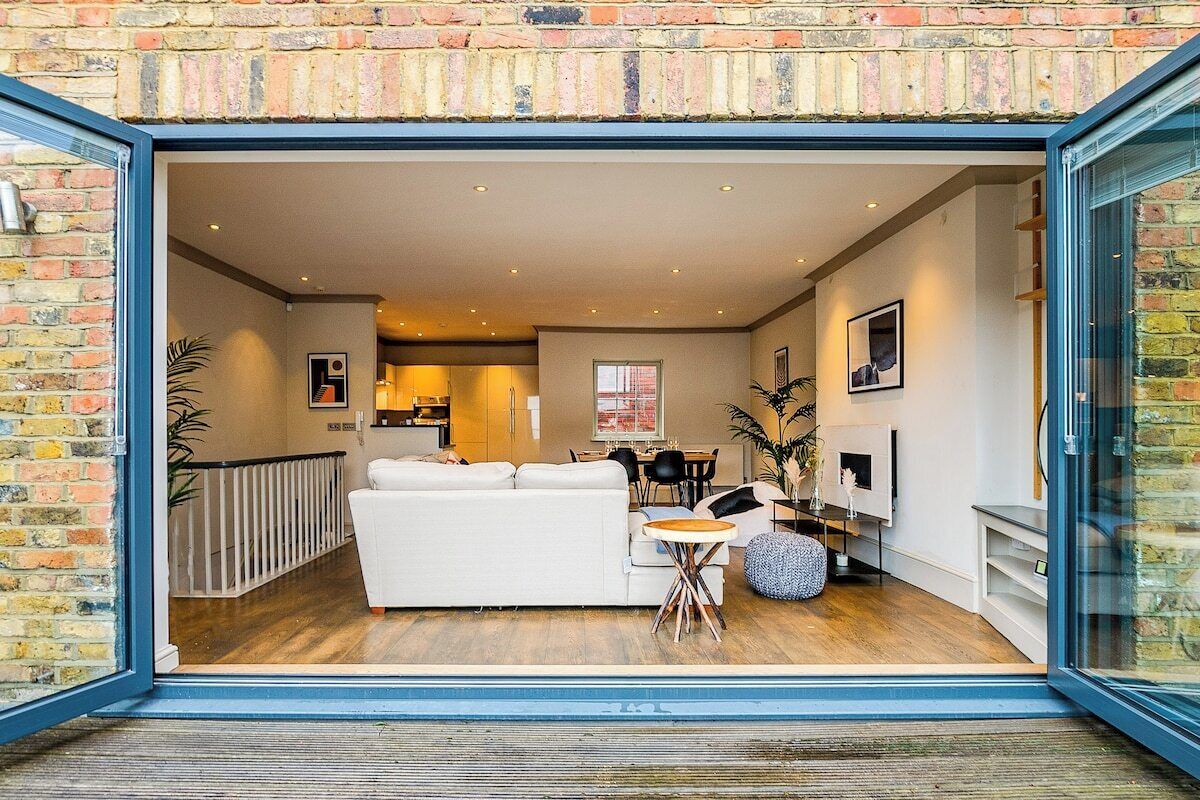 A modern interior with a white sofa, dining table, and chairs, a fireplace, and a brick wall.