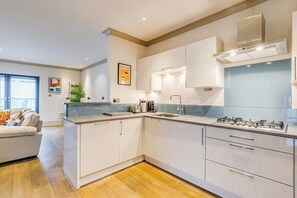 A modern kitchen with white cabinetry, a stainless steel range hood, and a built-in oven. - Charming  Spacious 5 Bed Mews House - Kensington (Greater London)