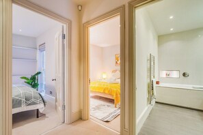 A hotel room with a bed, a bedside table, a radiator, and a window with a plant. - Charming  Spacious 5 Bed Mews House - Kensington (Greater London)