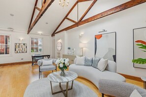 Ein modernes Wohnzimmer mit einem gebogenen Sofa, einem runden Couchtisch und einer Deckenleuchte.