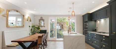 A modern kitchen with a central island, dark cabinetry, and pendant lighting.