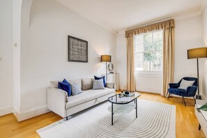 A modern living room with a sofa, coffee table, and two lamps. - Belgravia - Charming   Spacious 4 Bed Home for 9 (Greater London)