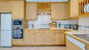 Une cuisine avec des meubles de rangement en bois, un four à micro-ondes, un grille-pain et un lave-vaisselle.
