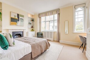A well-lit bedroom with a bed, a radiator, a window, and a chair. - Belgravia - Charming   Spacious 4 Bed Home for 9 (Greater London)
