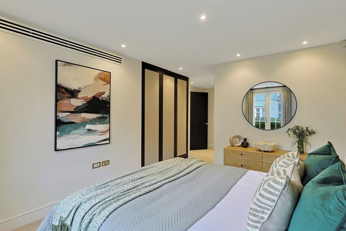 Un dormitorio moderno con cama, obras de arte, un espejo y un aparador.