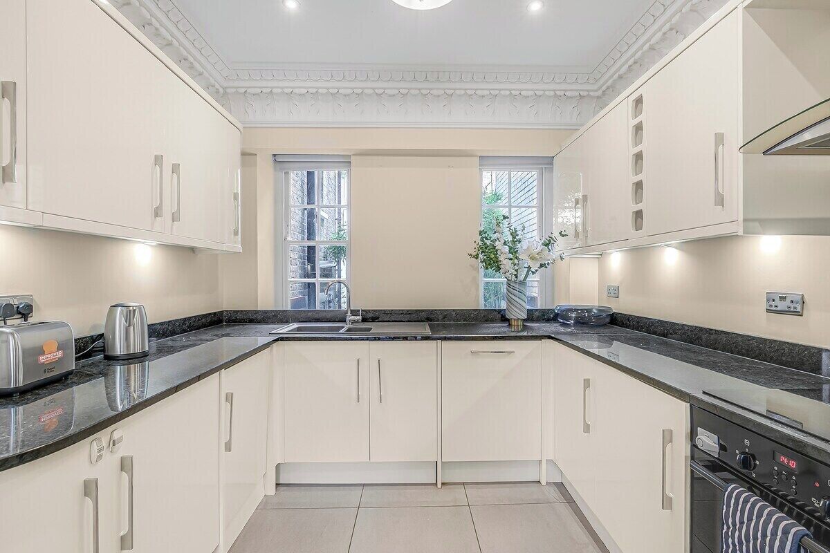 A modern kitchen with white cabinetry, a granite countertop, and a built-in oven.