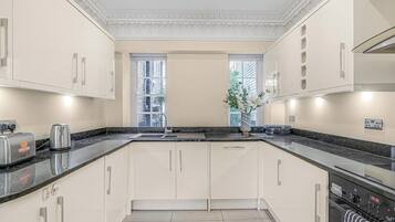 A modern kitchen with white cabinetry, a granite countertop, and a built-in oven.