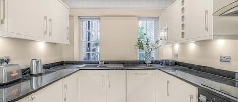 A modern kitchen with white cabinetry, a granite countertop, and a built-in oven.