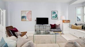 Uma sala de estar moderna com televisão de tela plana, assentos confortáveis e obras de arte nas paredes.