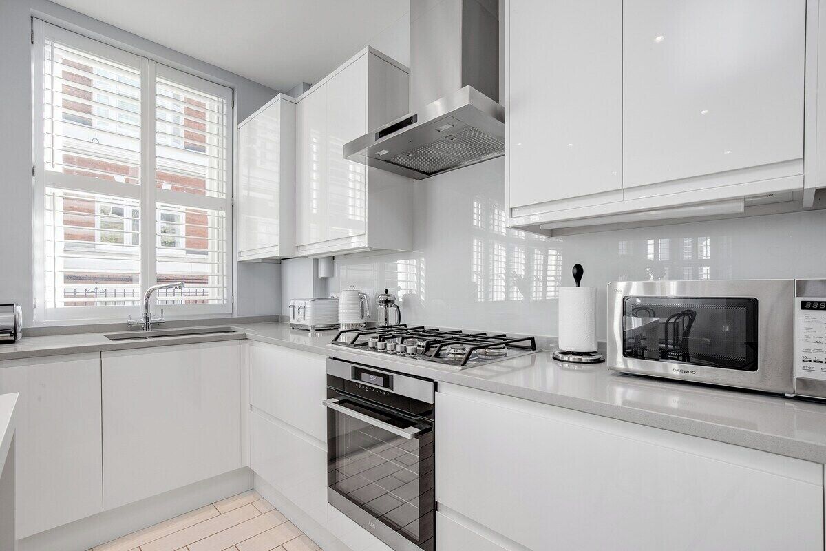 A modern kitchen with white cabinetry, a gas stove, an oven, and a microwave.