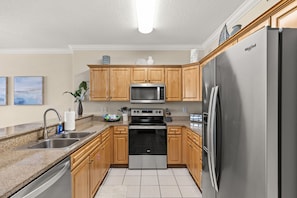 A modern kitchen with wooden cabinets, stainless steel appliances, and a granite countertop. - Ocean Villa 901 ~ beachfront 2 bed 2 bath condo in Panama City Beach (Panama City Beach)