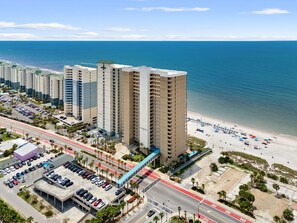 Ein Hochhaus-Hotel mit mehreren Etagen, einem Parkplatz und Blick auf den Strand.