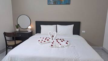 A hotel room with a neatly made bed, a bedside table with a lamp, a chair, and a painting on the wall.