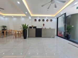 A reception area with a reception desk, chairs, potted plants, and wall clocks indicating different cities.