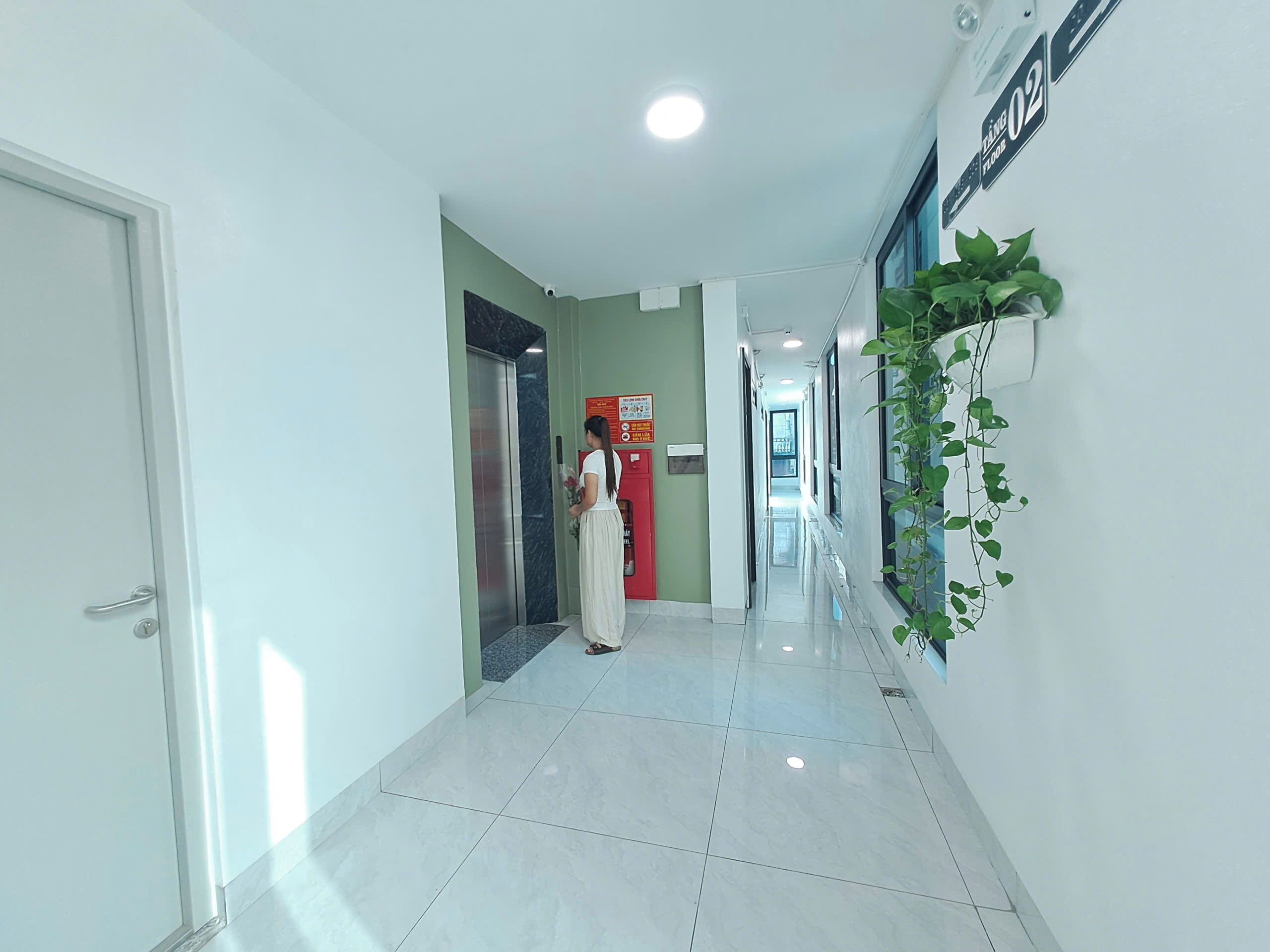 A hallway with a tiled floor, a red elevator, and a wall-mounted sign.