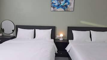 A hotel room with two beds, a bedside table with a lamp, a round mirror, and a painting on the wall.