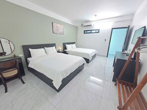 A hotel room with two beds, a desk, a chair, a TV, and a bathroom door.