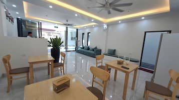 A modern hotel lobby with a reception desk, seating area, and a large potted plant.