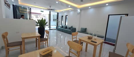 Un moderno vestíbulo de hotel con una recepción, zona de asientos y una planta grande en maceta.