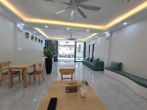 A modern hotel lobby with a reception desk, seating area, and a view of the street.