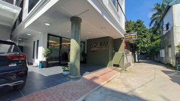 The entrance of Noibai Transit Hotel with a tiled pavement, a parked car, and a signboard.